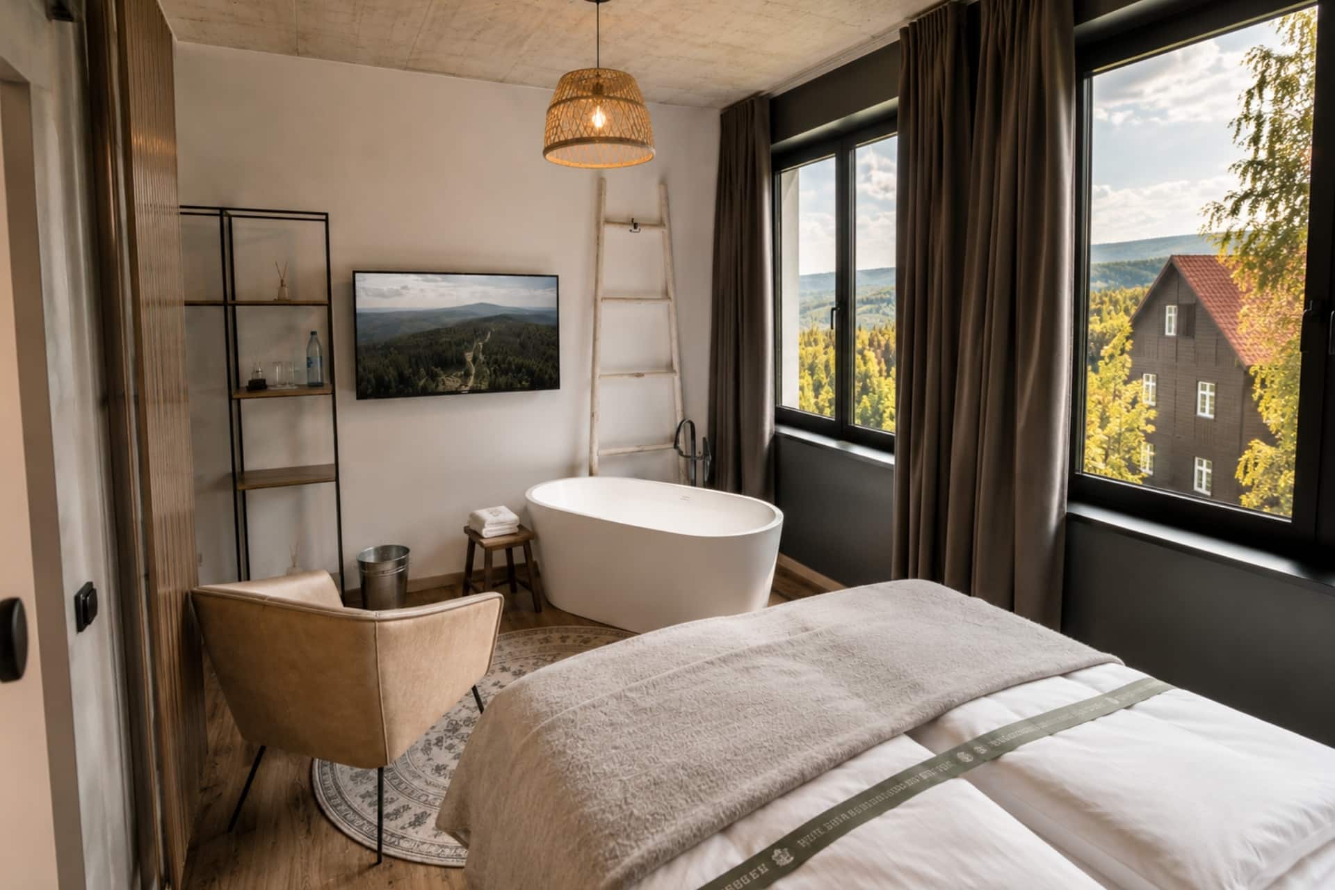 Helle Unterkunft mit Blick auf eine Landschaft, freistehende Badewanne, Fernseher, Sessel und modernes Interieur.